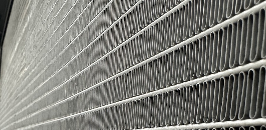 Close-up of an outdoor HVAC coil with metal fins and tubing